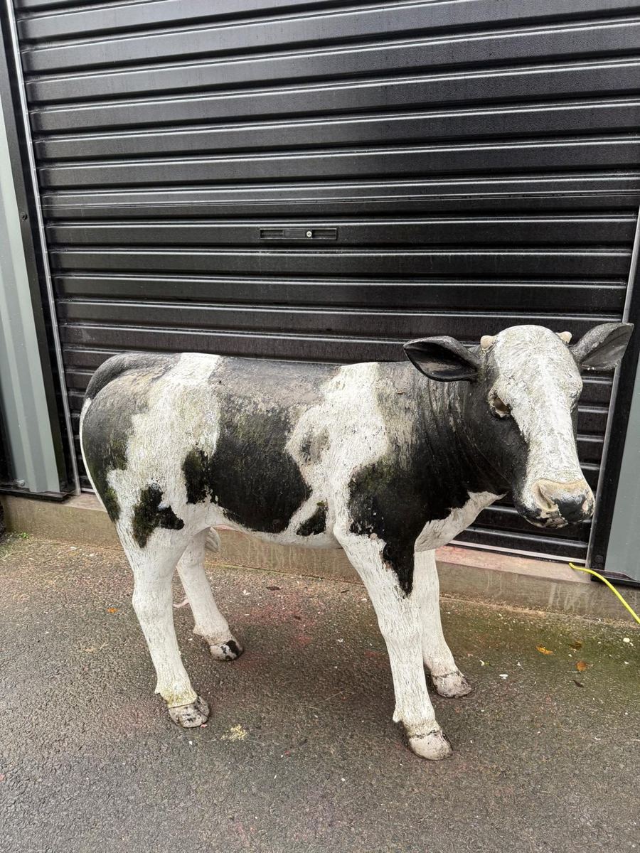 Weathered calf statue with flaking paint and moss