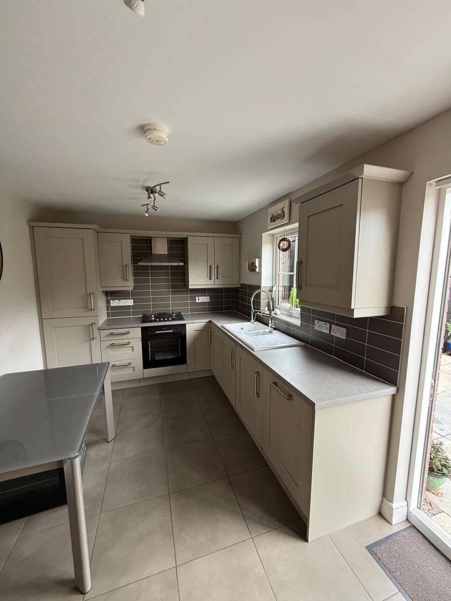 The same kitchen with light grey worktops and a white ceramic sink
