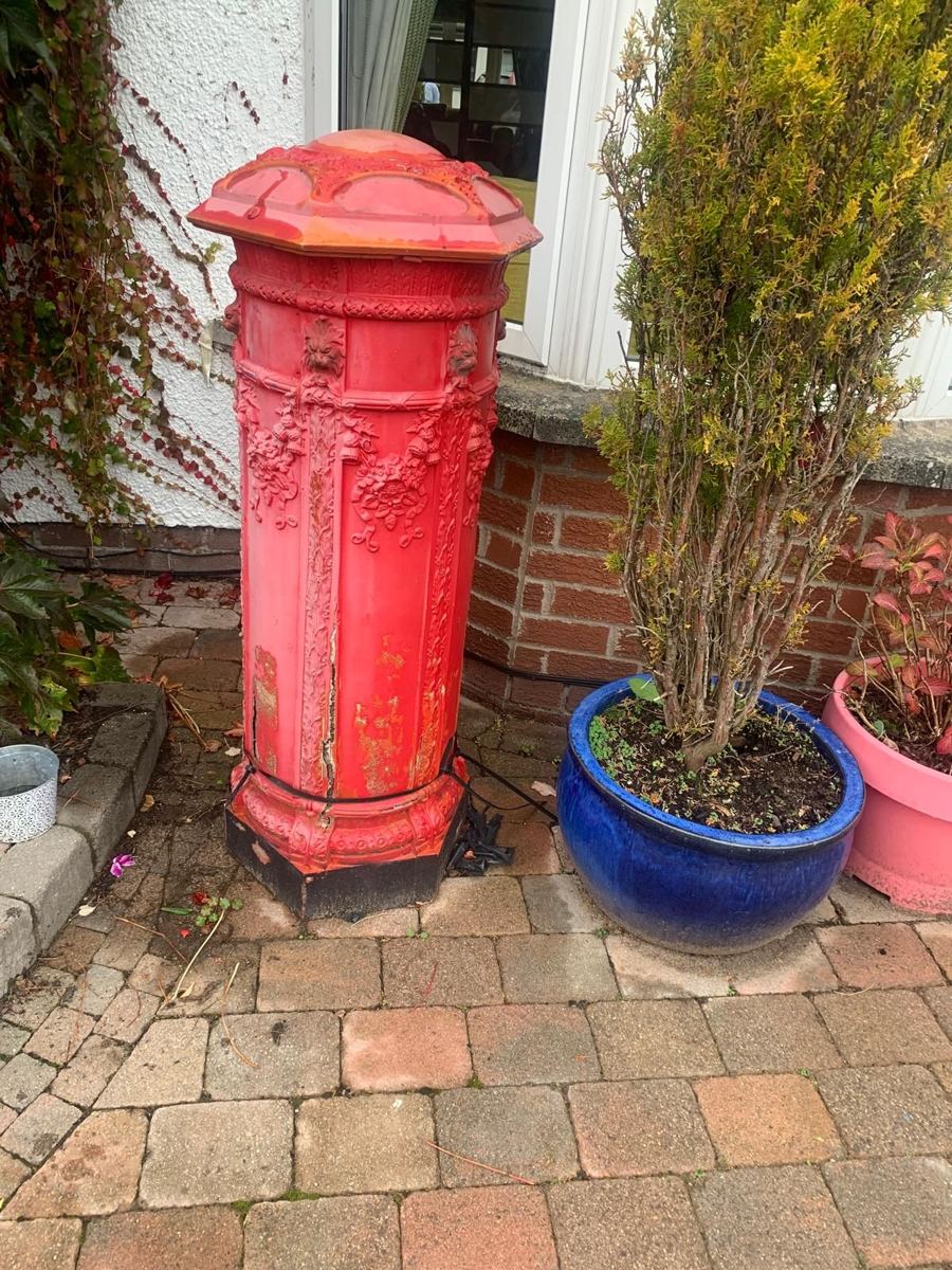 Faded red post box with a large crack and peeling paint